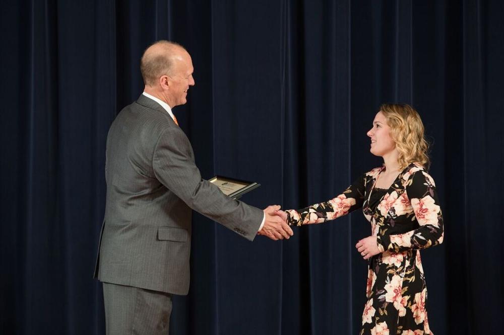 Doctor Potteiger shaking hands with an award recipient in a black and floral dress